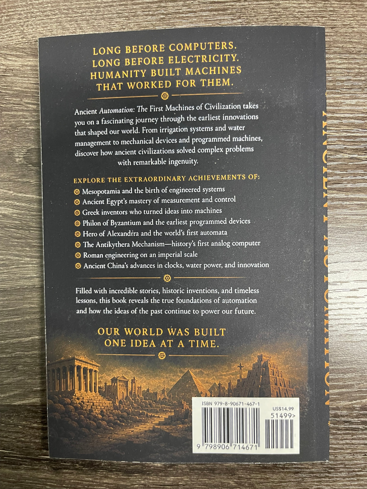 The back cover of a book titled 'Long Before Computers' resting on a dark wood surface. The cover is predominantly black with gold and white text, featuring a historical illustration of the Parthenon at the bottom and a gold vertical stripe pattern on the right edge.